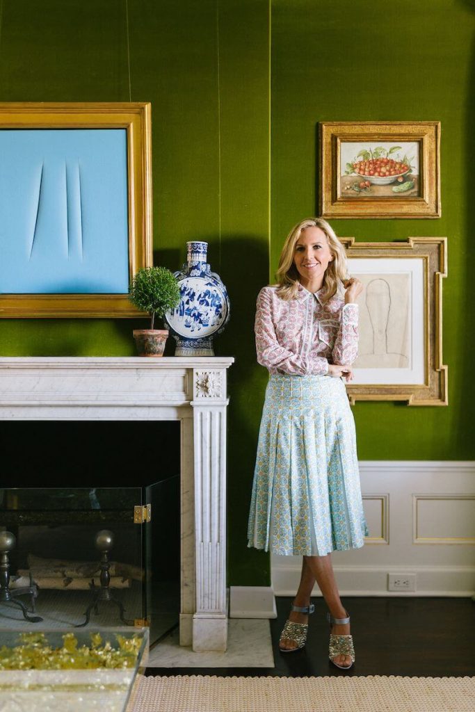 Tory Burch standing by her fireplace. 
