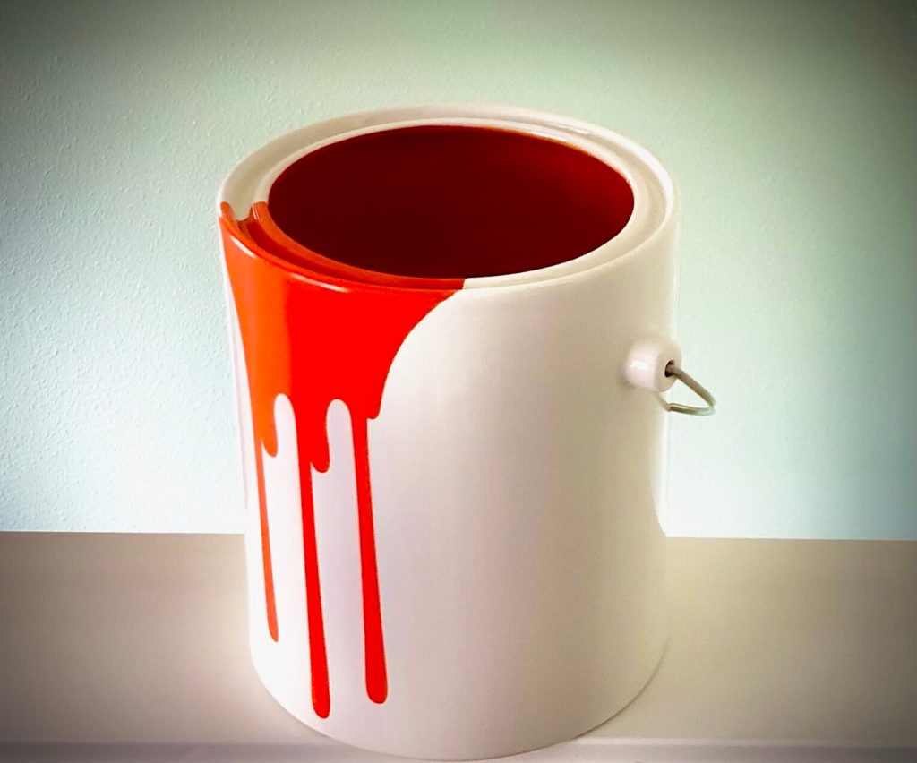 A paint bucket with dried orang paint.