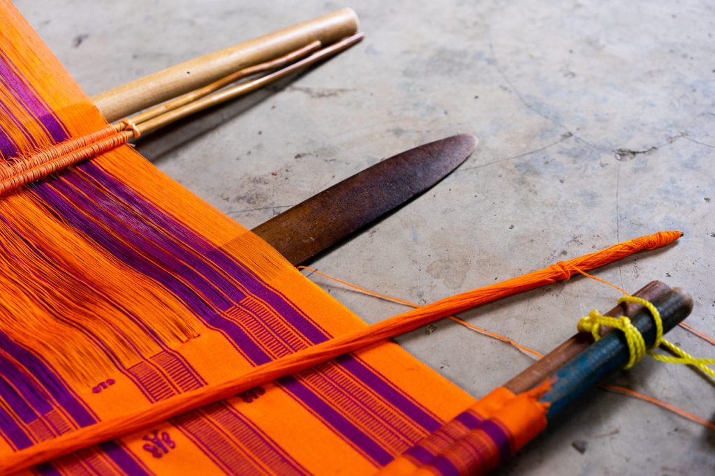 bright orange and purple Mexican textile on a loom.