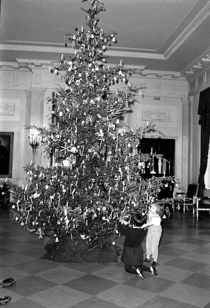 Caroline Kennedy and a friend decorate the 1962 White House Christmas tree.