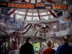Alan Grant, Ellie Sattler, and Ian Malcolm marvel at the grand rotunda as they enter the visitor’s center of Jurassic Park.